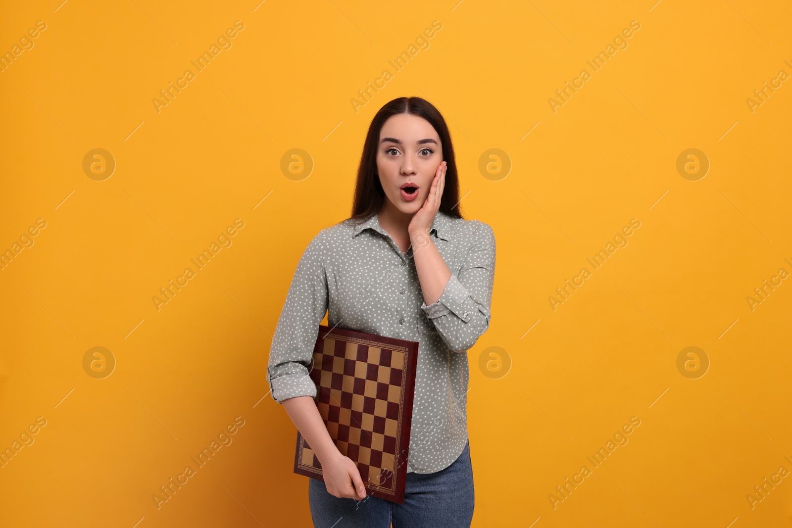 Photo of Emotional woman with chessboard on orange background