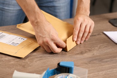 Photo of Post office worker sealing adhesive paper bag at counter indoors, closeup