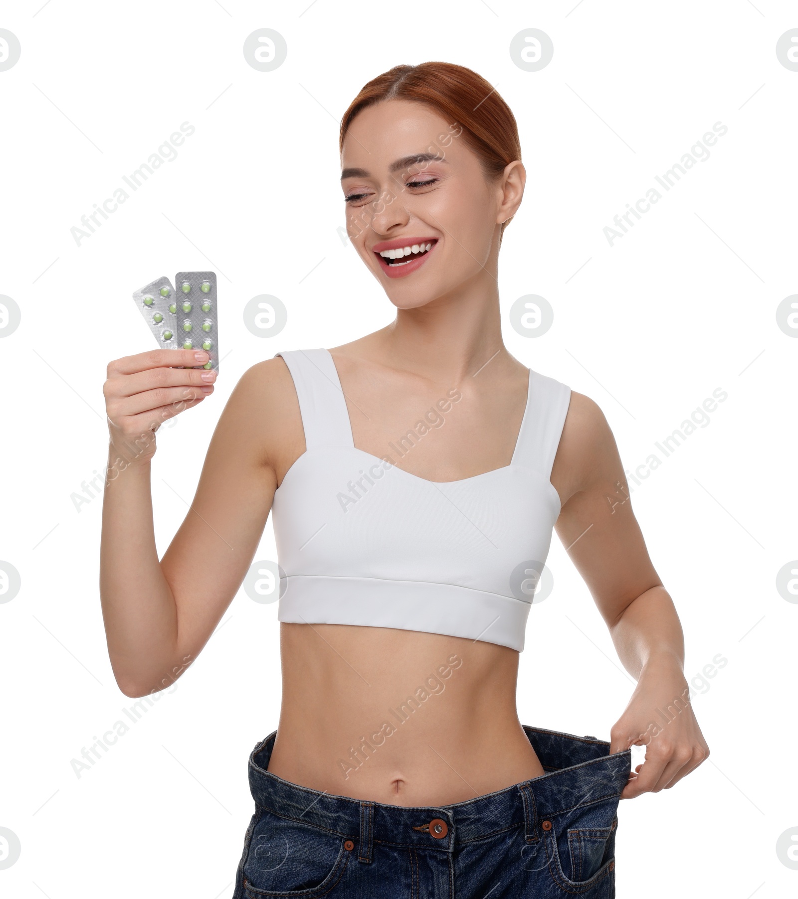 Photo of Slim woman in big jeans with pills on white background. Weight loss