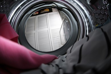 Photo of Clothes in washing machine indoors, view from inside. Laundry day