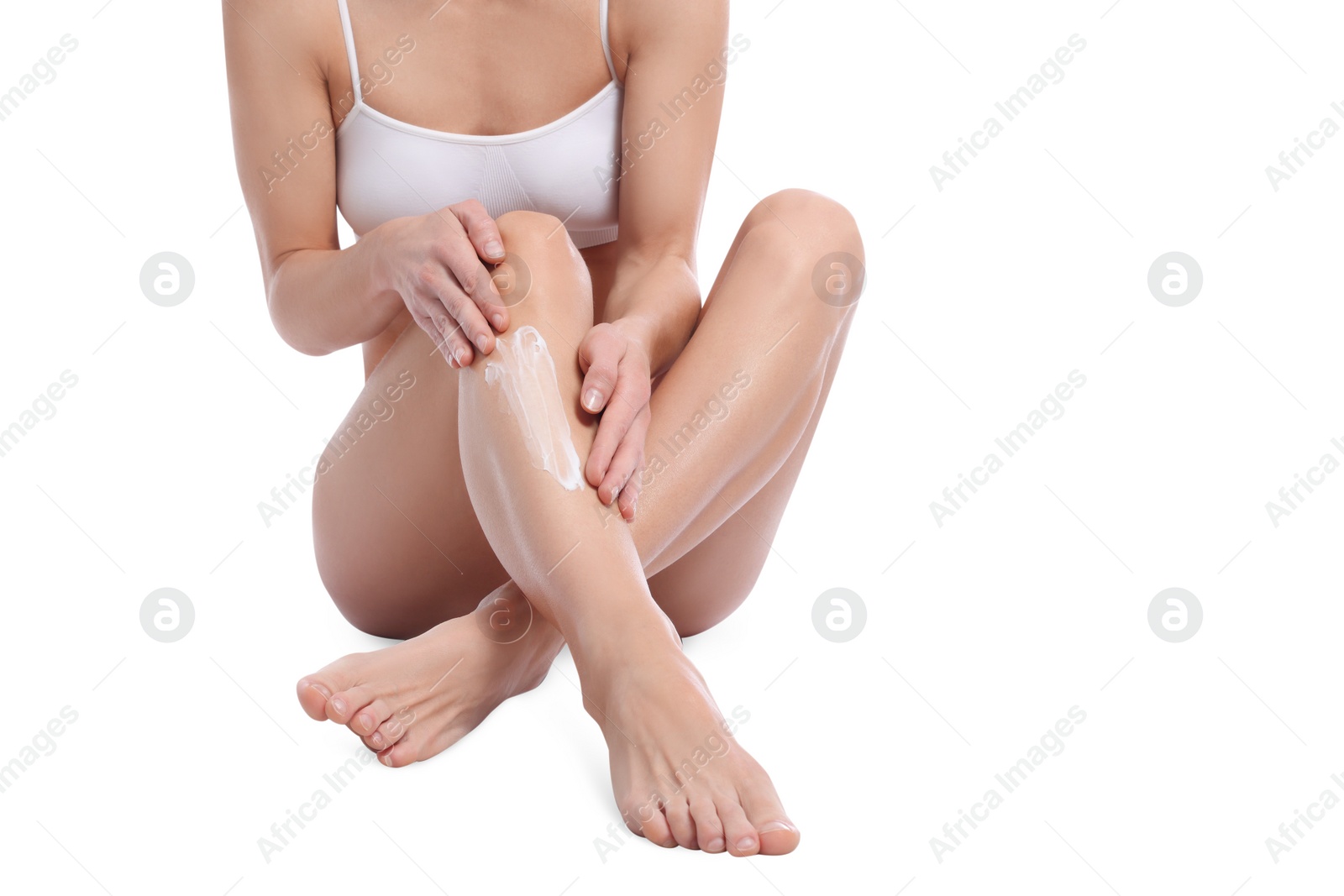 Photo of Woman applying body cream onto her leg against white background, closeup