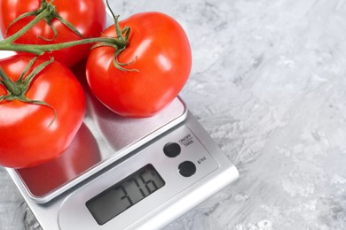 Photo of Kitchen scale with tomatoes on grey textured table, closeup. Space for text