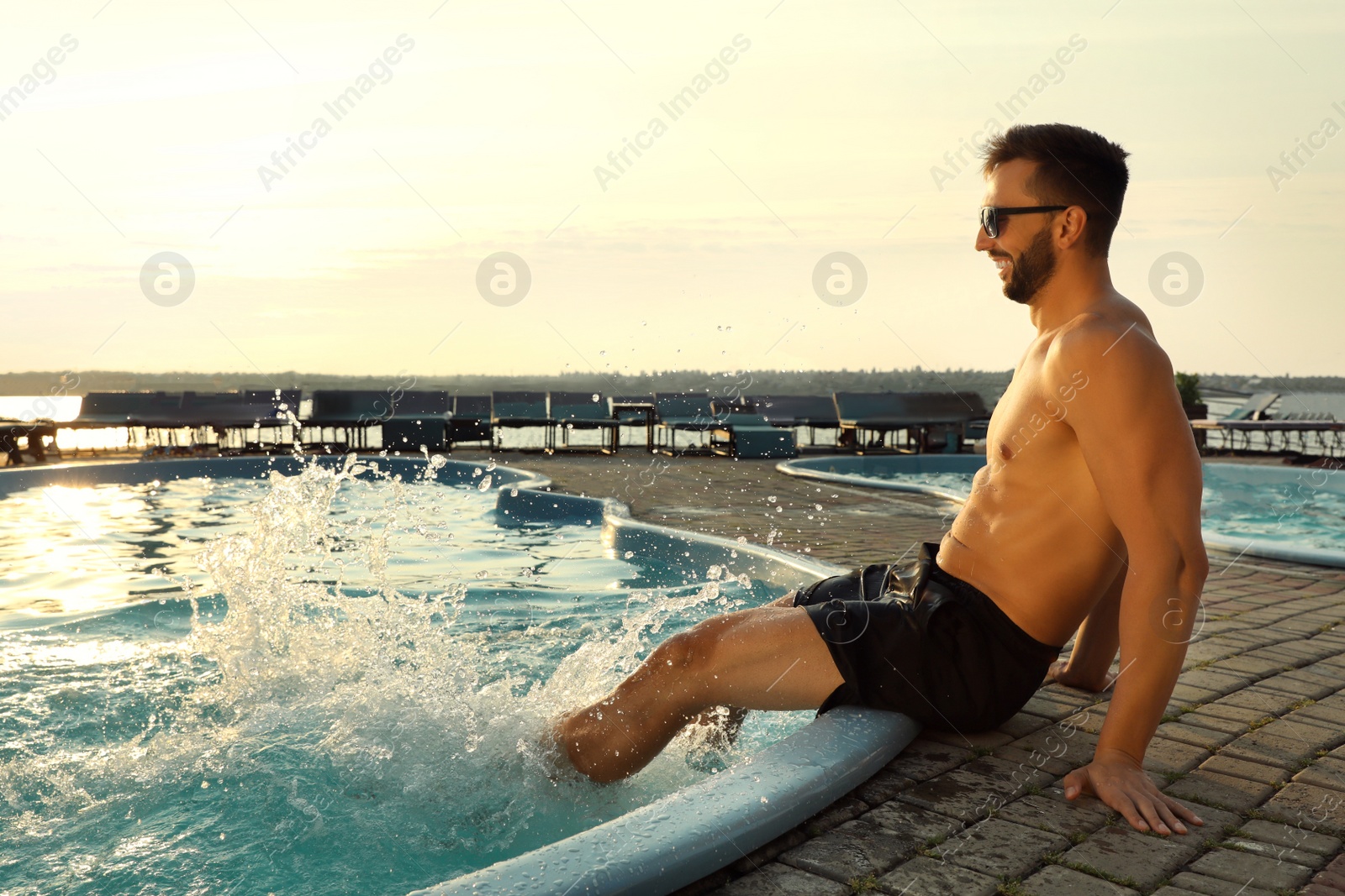 Photo of Happy man having fun near outdoor swimming pool on summer day