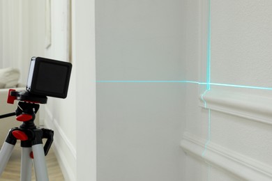 Cross line laser level on tripod in front of white wall
