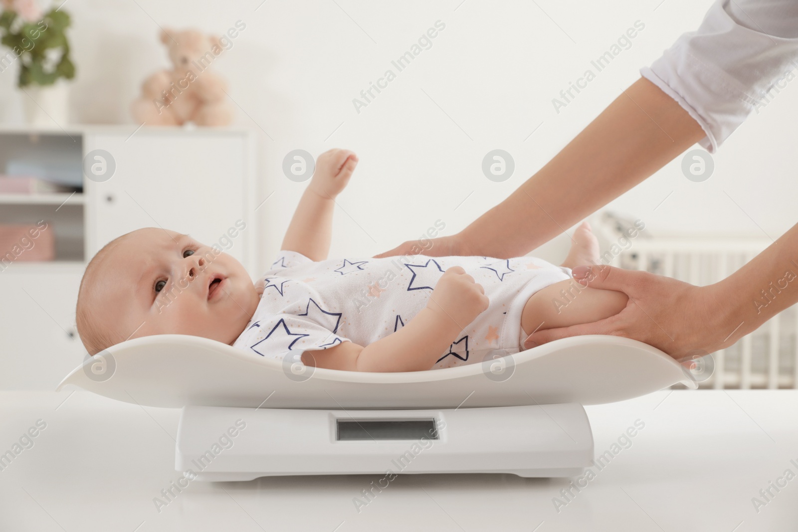 Photo of Doctor weighting baby on scales in light room