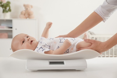 Doctor weighting baby on scales in light room