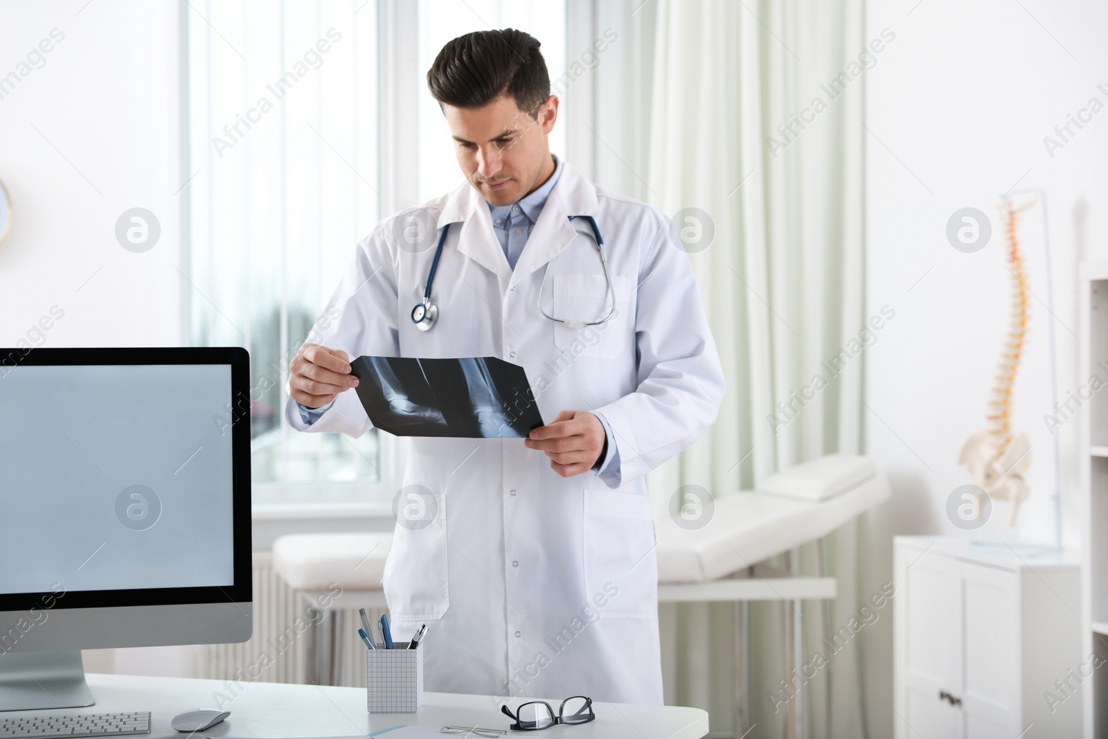 Photo of Professional orthopedist examining X-ray picture in clinic