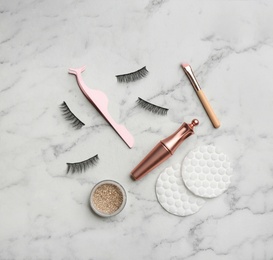 Flat lay composition with magnetic eyelashes and accessories on white marble table