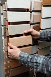 Man choosing wooden flooring among different samples in shop, closeup