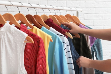 Photo of Woman choosing clothes from wardrobe rack, closeup