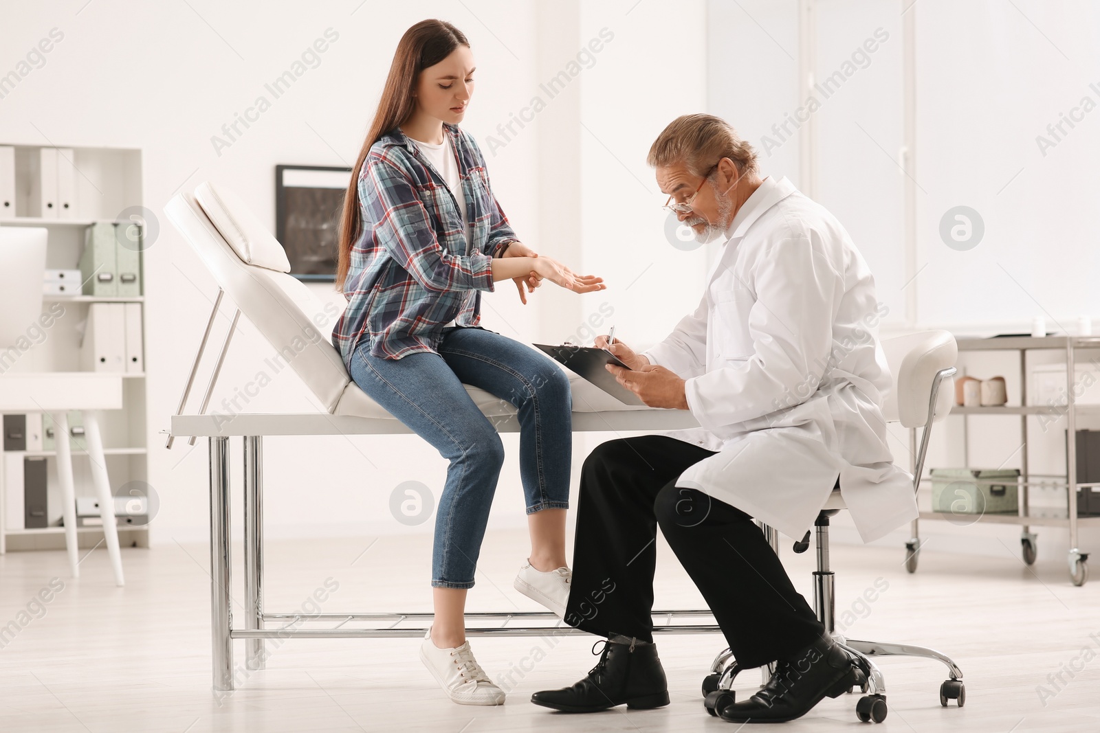 Photo of Orthopedist examining patient with injured hand in clinic