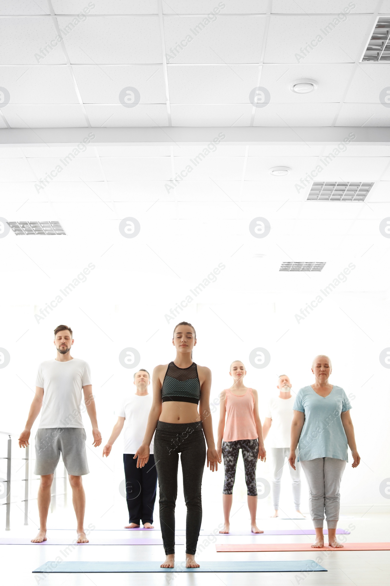 Photo of Group of people in sportswear practicing yoga indoors