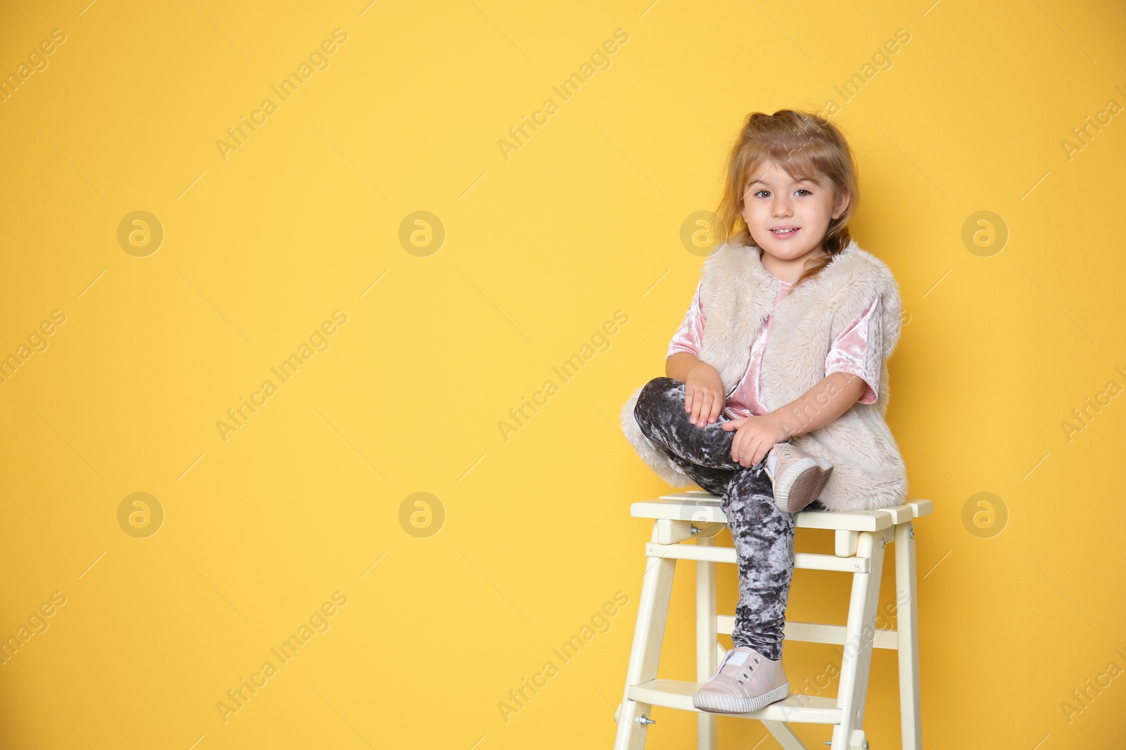 Photo of Little girl in trendy outfit on color background