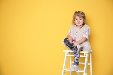 Little girl in trendy outfit on color background