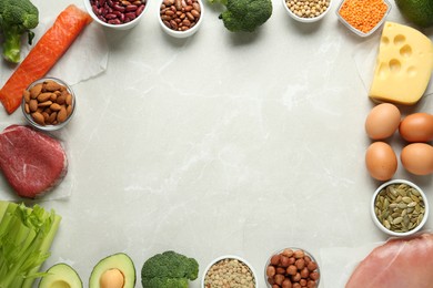 Photo of Frame of products rich in amino acids on light grey table, flat lay. Space for text