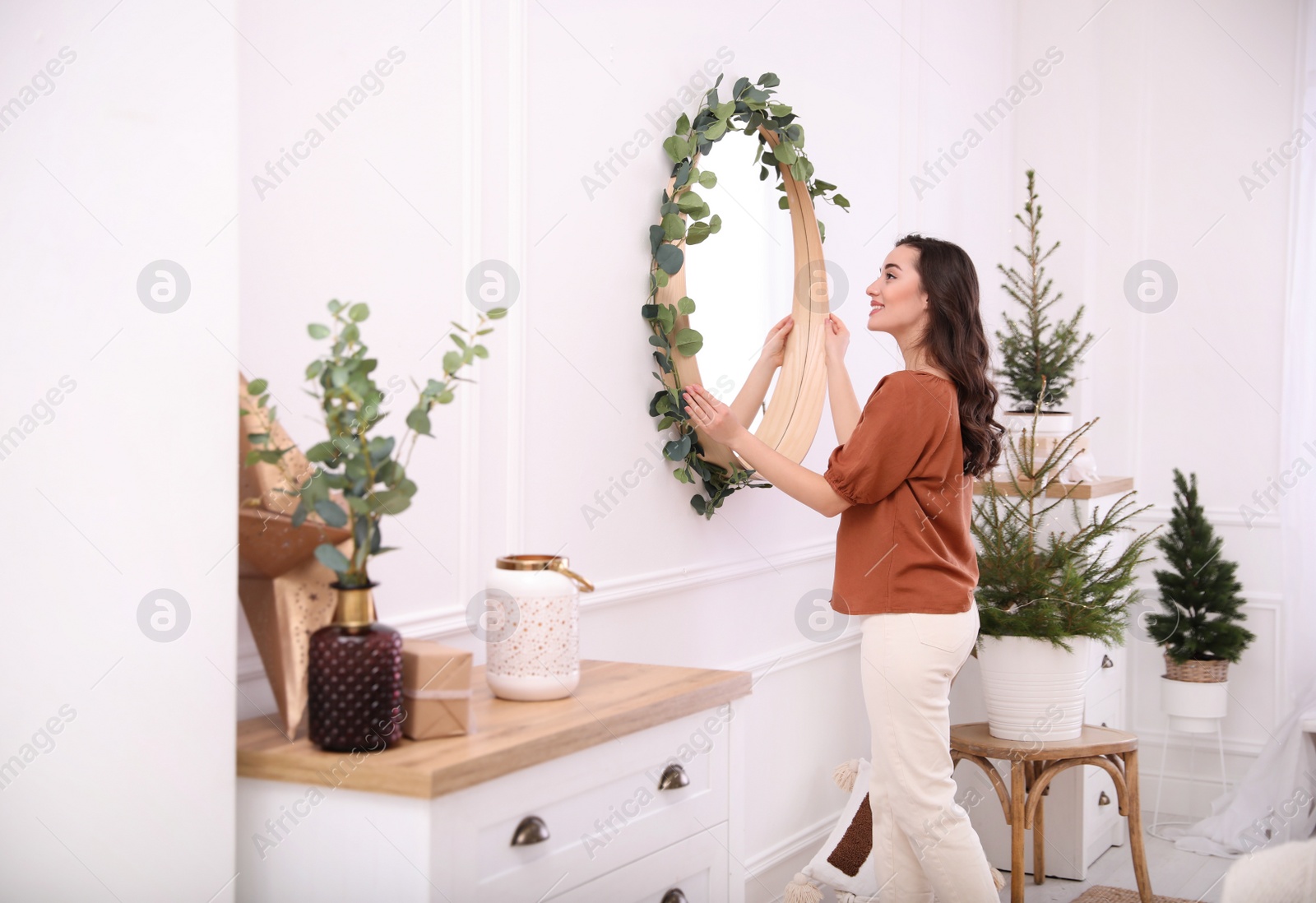 Photo of Woman decorating mirror with eucalyptus branches at home