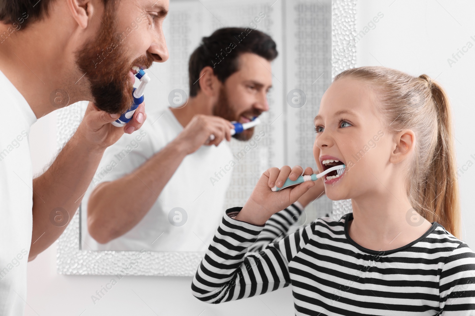 Photo of Father and his daughter brushing teeth together in bathroom