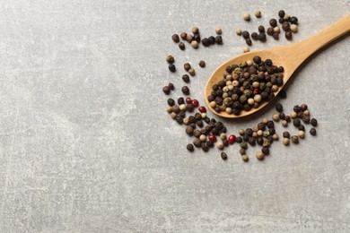 Photo of Aromatic spice. Different peppers in spoon on grey table, top view. Space for text