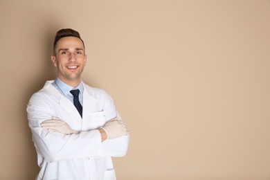 Photo of Portrait of male dentist on color background. Space for text