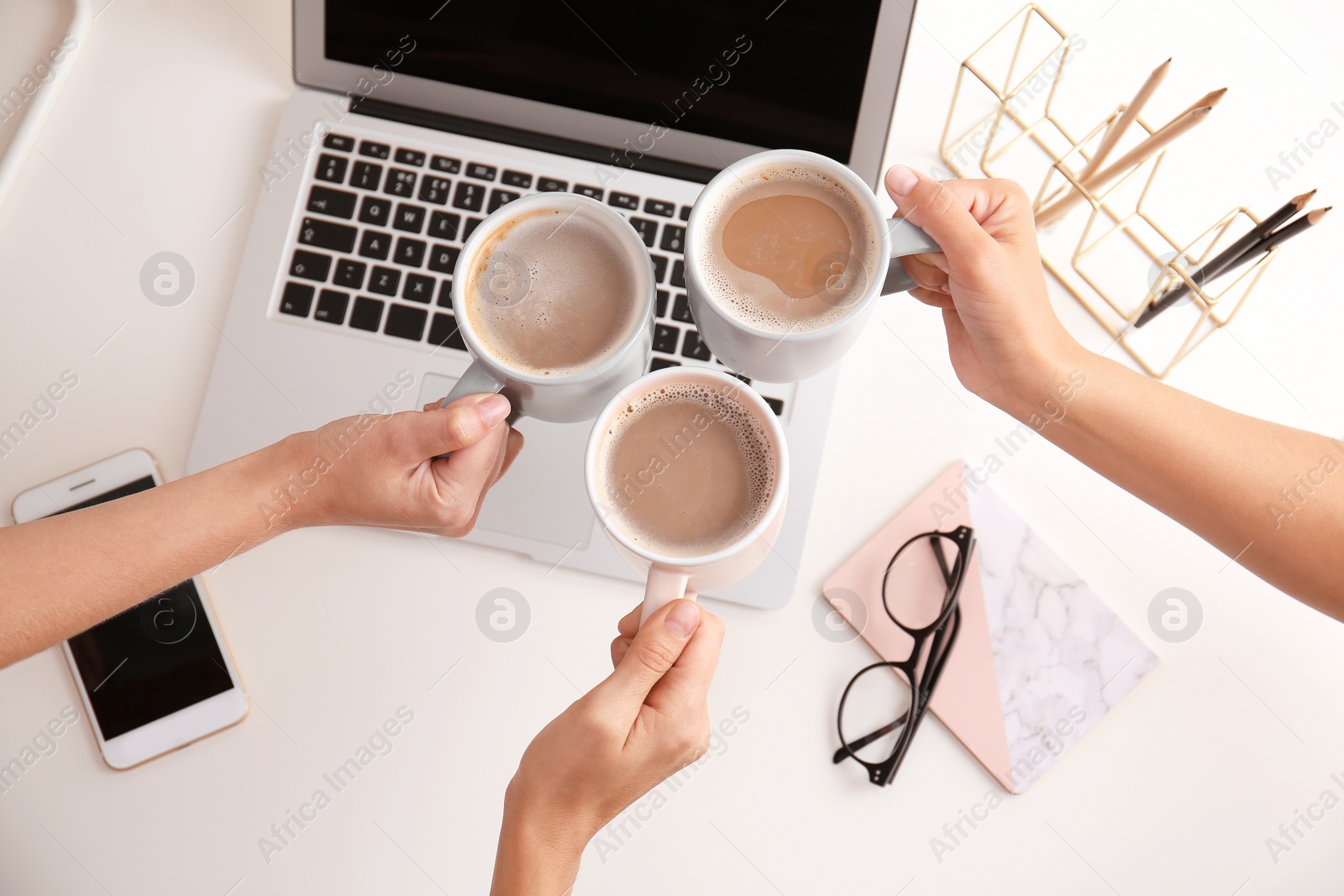 Photo of Women holding coffee cups at modern workplace in office, top view