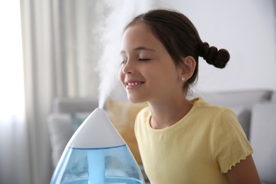 Photo of Little girl near modern air humidifier at home