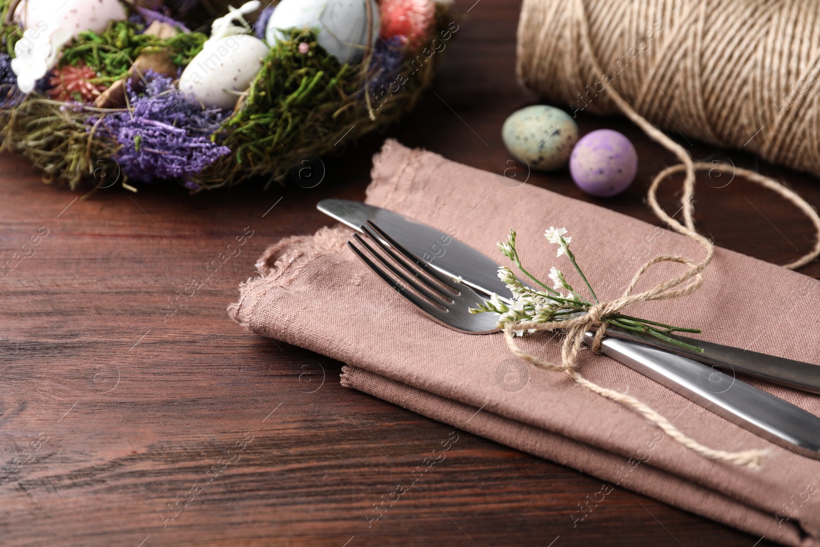 Photo of Cutlery set with quail eggs on wooden table, closeup. Easter celebration