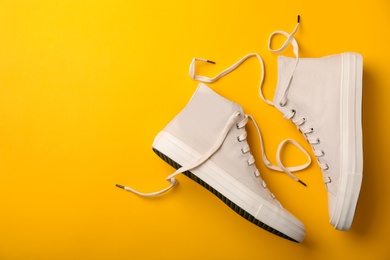 Photo of Pair of white sneakers on color background, top view