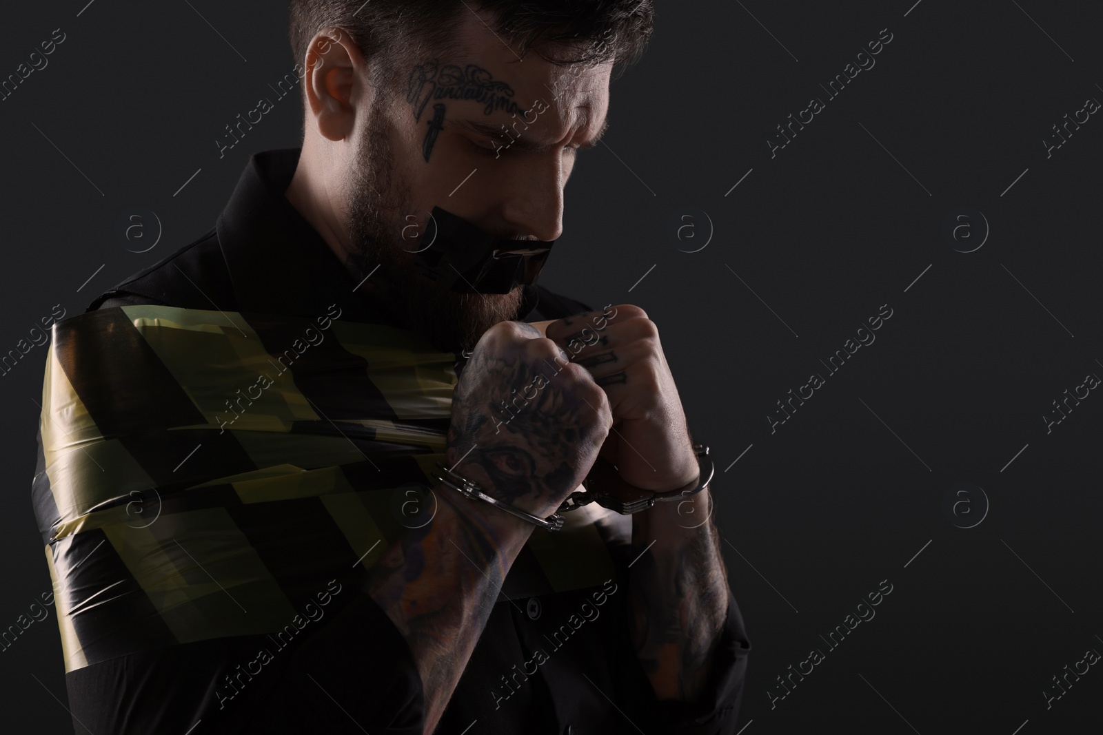 Photo of Man taped up and taken hostage on dark background. Space for text