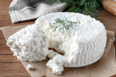 Delicious cottage cheese with dill on wooden table, closeup