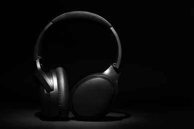 Photo of Modern wireless headphones on black background, space for text