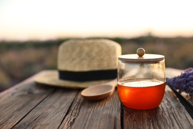 Photo of Fresh lavender honey on wooden table outdoors. Space for text.