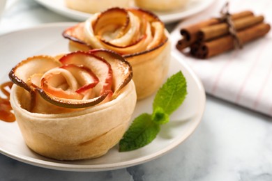 Freshly baked apple roses served on white marble table, closeup. Beautiful dessert