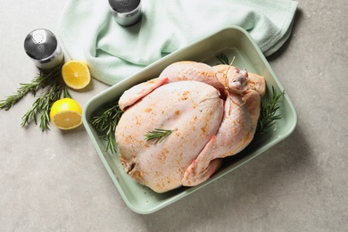 Photo of Dish with raw spiced turkey and rosemary on light background, top view