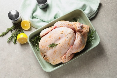 Dish with raw spiced turkey and rosemary on light background, top view