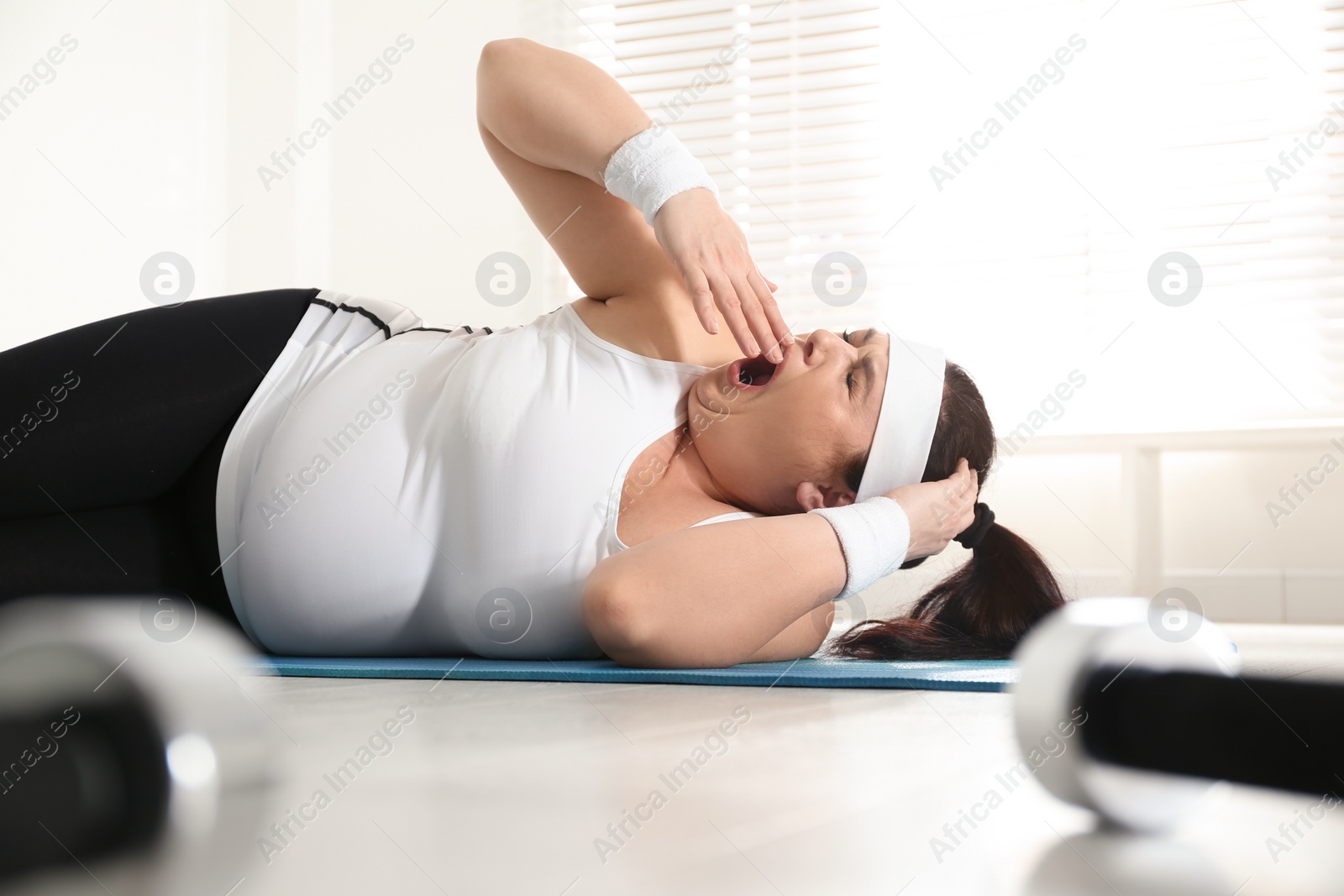 Photo of Lazy overweight woman sleeping instead of training on mat at gym