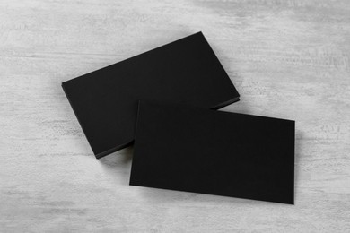 Blank black business cards on white table, above view. Mockup for design