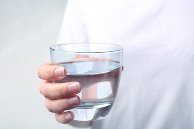 Photo of Woman holding glass with fresh water against light background, closeup