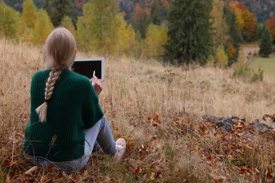 Young woman drawing on tablet outdoors, back view