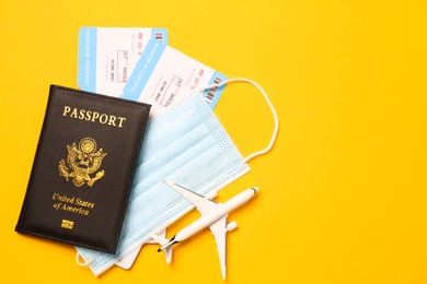 Photo of Flat lay composition with passport and protective mask on yellow background, space for text. Travel during quarantine