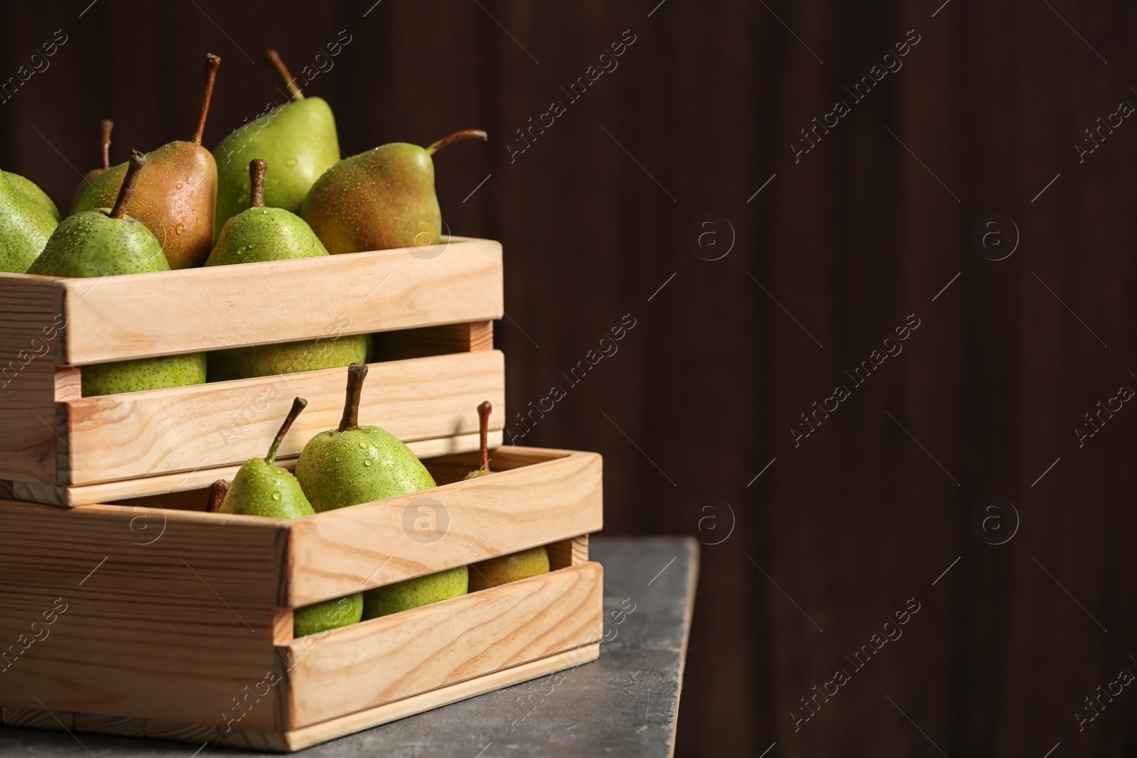 Photo of Wooden crates with ripe pears on table. Space for text