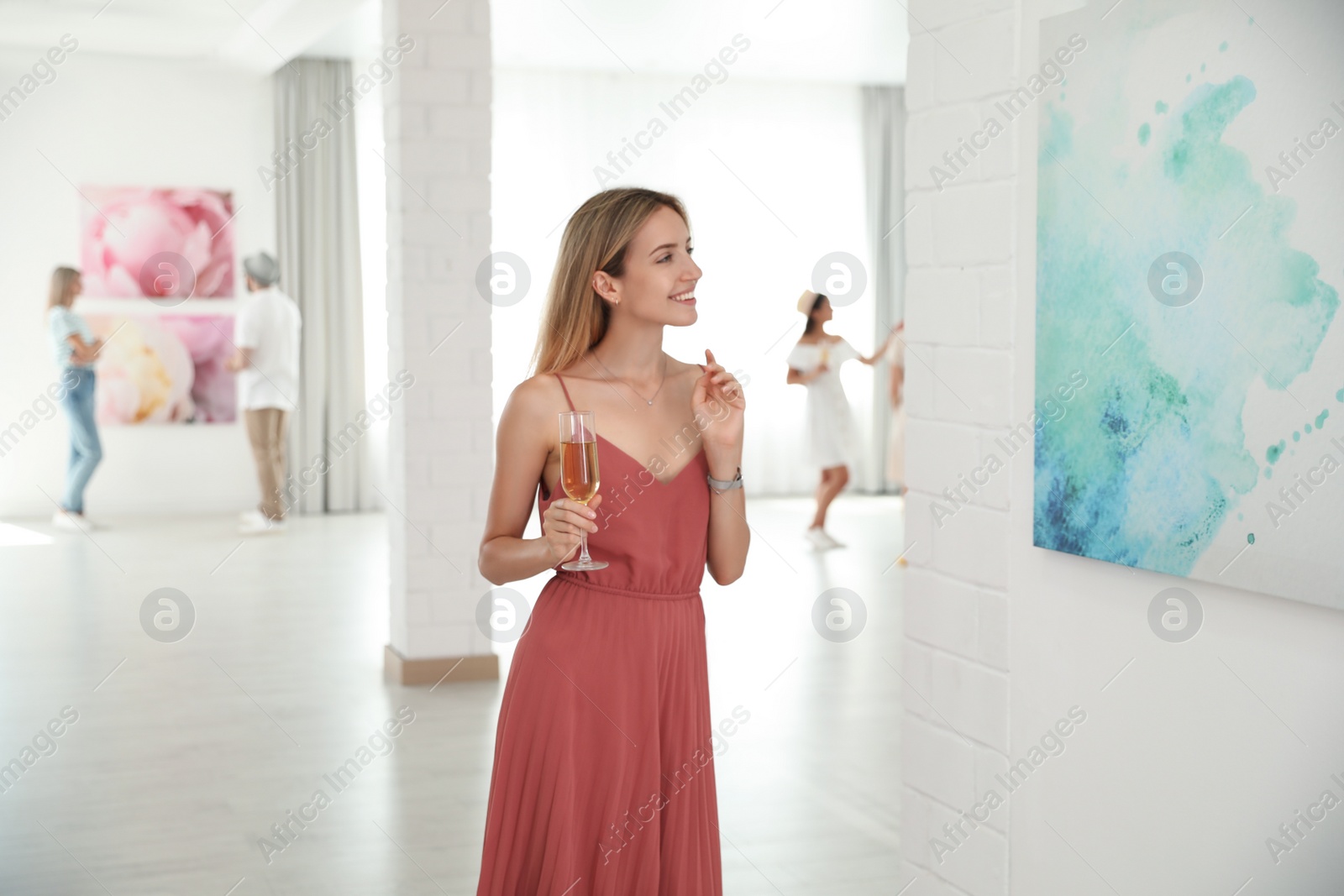 Photo of Young woman with glass of champagne at exhibition in art gallery