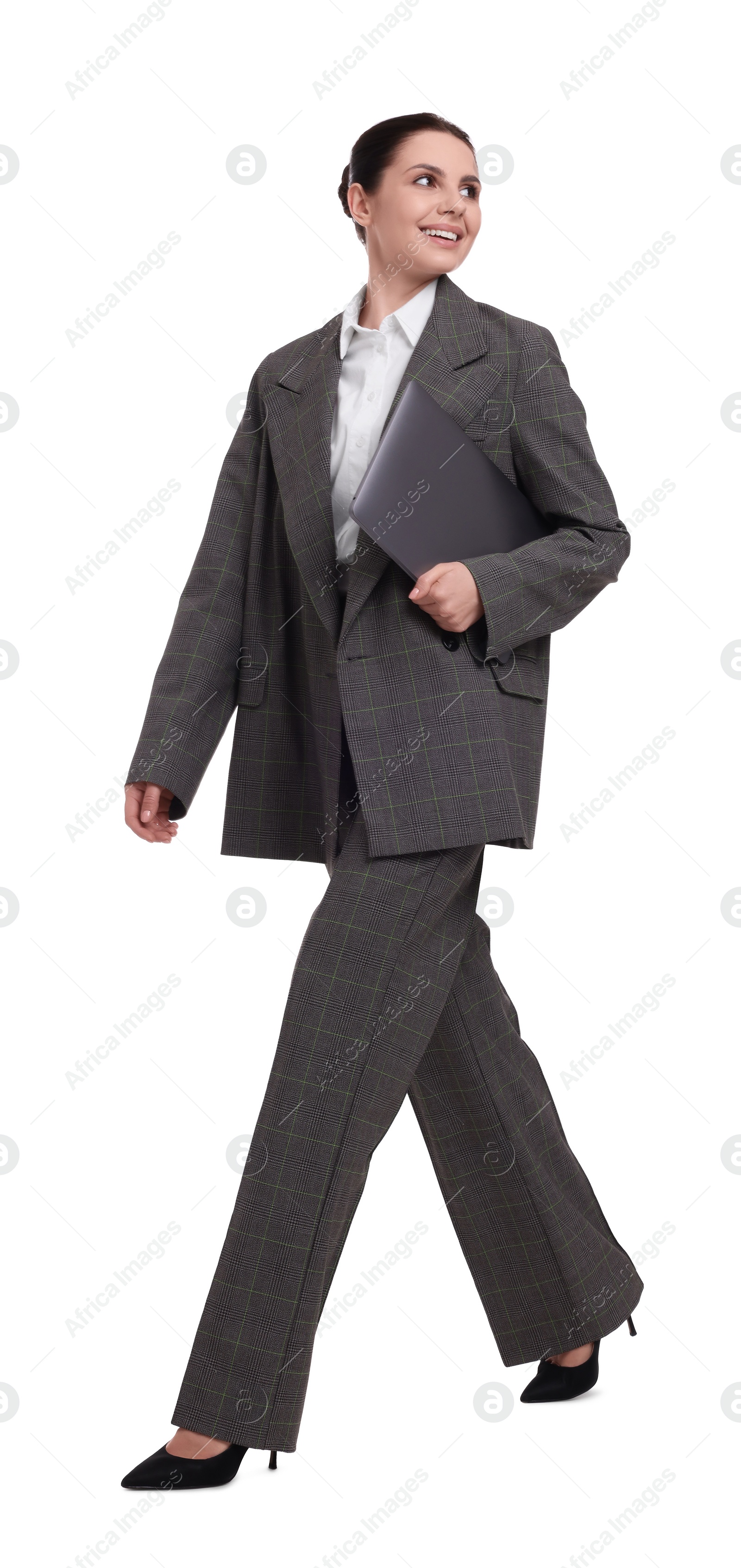 Photo of Beautiful businesswoman with laptop walking against white background