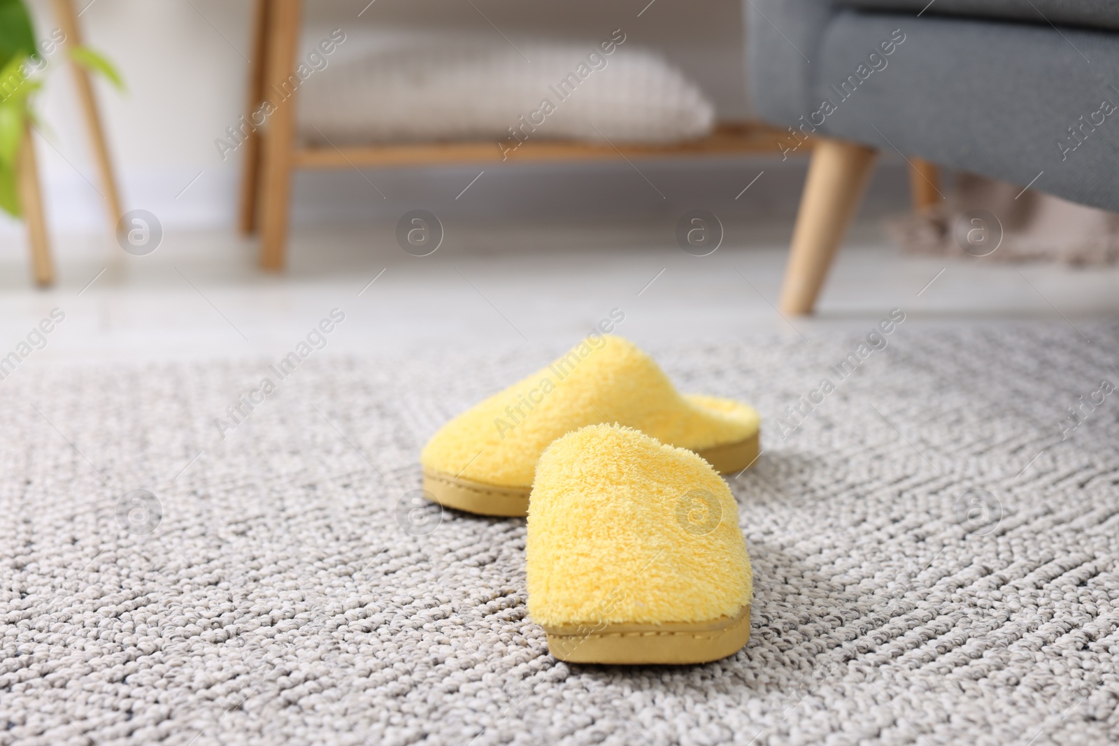 Photo of Yellow soft slippers on crochet carpet indoors, closeup