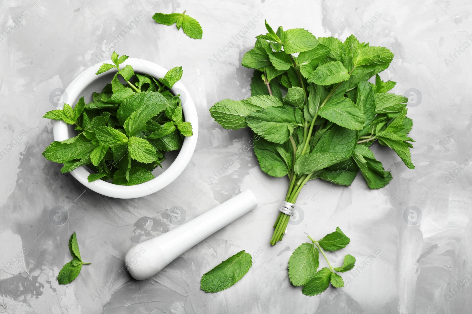 Photo of Fresh mint with mortar and pestle on grey marble table, flat lay