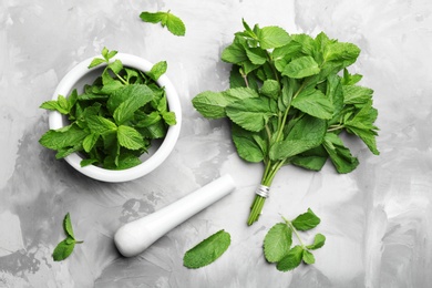 Fresh mint with mortar and pestle on grey marble table, flat lay