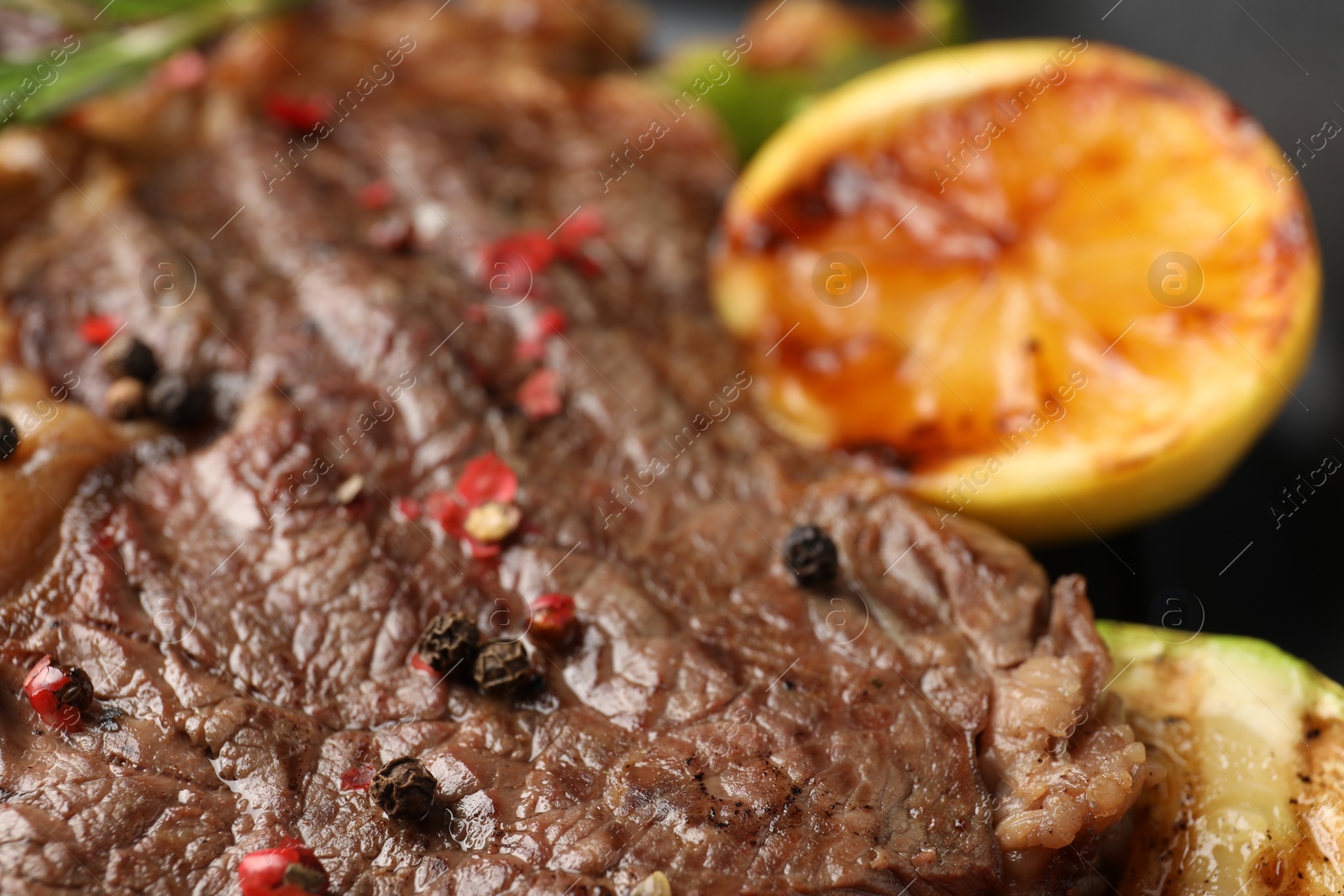 Photo of Delicious grilled beef steak and lemon, closeup
