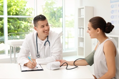 Doctor checking patient's blood pressure in hospital