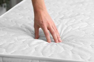 Man touching soft mattress indoors, closeup view