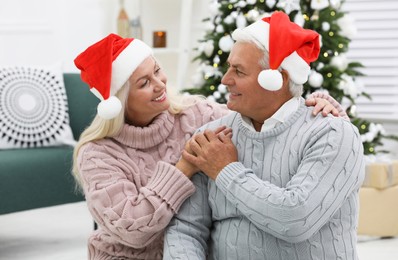 Photo of Happy mature couple in Santa hats at home. Christmas celebration