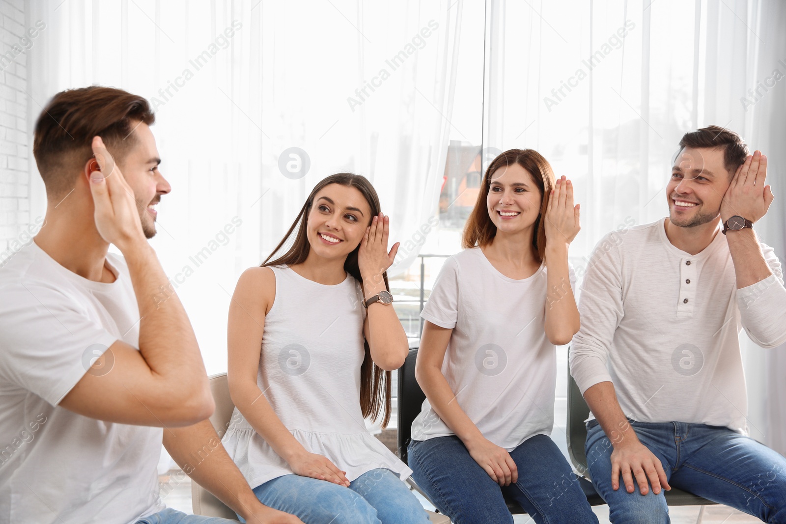 Photo of Group of young people learning sign language with teacher indoors